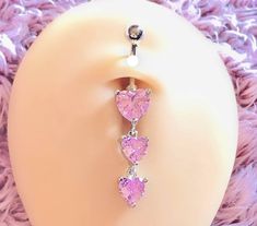 three heart shaped pink stones hang from an earring on a mannequin's head