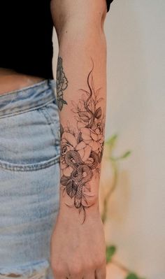 a woman's arm with flowers and butterflies tattooed on the left side of her arm