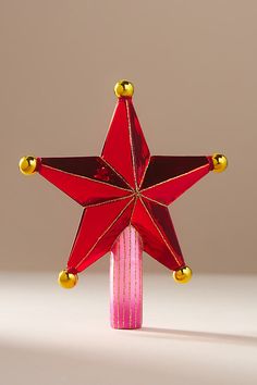 a red and gold star ornament sitting on top of a wooden pole