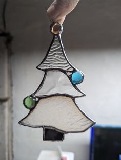 a stained glass christmas tree ornament being held by a hand