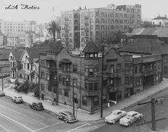 an old black and white photo of cars parked in front of buildings on the street