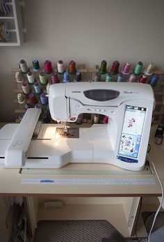 a white sewing machine sitting on top of a table next to a bunch of spools of thread