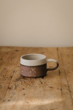 a brown and white cup sitting on top of a wooden table