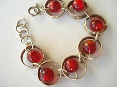 A very pretty, bright bracelet made from silver tone metal swirls with a red glass bead in the centre of each circle.  An unusual design Difficult to date this item so I have described it as 60's. The bracelet has a good  safety clasp and measures almost 7 3/4 inches (19.5 cms) including the clasp..   Please let me know if you need any more information or photos. For more great vintage and Art Deco jewellery go to - http://www.etsy.com/shop/jemimajay?ref=si_shop Retro Red Metal Jewelry, Red Retro Metal Jewelry, Red Metal Beaded Bracelet With Round Beads, Red Metal Costume Jewelry Bracelets, Red Metal Costume Jewelry Bracelet, Nickel-free Red Metal Bracelets, Red Nickel-free Metal Bracelets, Nickel-free Red Metal Bracelet, Red Nickel-free Metal Bracelet