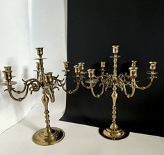 two brass candelabra stands next to each other