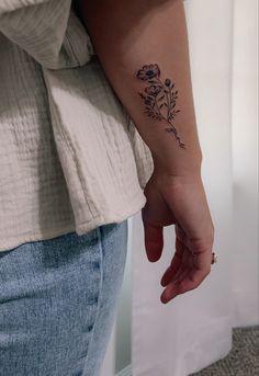 a woman's left arm with a flower tattoo on her left wrist and right hand