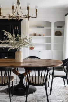 a dining room table with chairs and a vase filled with flowers on top of it