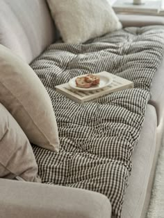 a couch with some food on top of it next to pillows and a window in the background