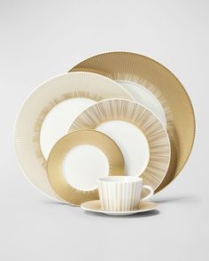 the gold and white dishes are stacked on top of each other, with one cup in front