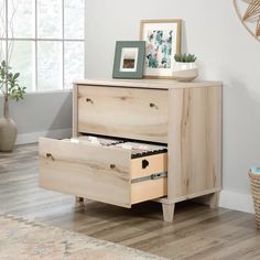 a wooden dresser with two drawers on top of it in a living room next to a potted plant