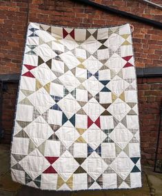 an old quilt hanging on the side of a brick building