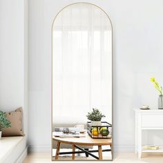 a living room with white walls and wooden flooring, a round mirror on the wall