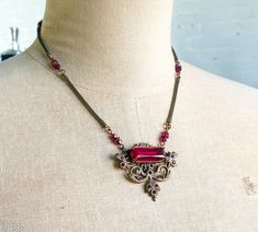 "~ 1940s garnet red glass & bronze necklace ~ Intricate setting with a faceted red glass stone ~ Pendant style necklace with small red glass beads ~ Coil necklace chain ~ Excellent Length- 17\" (43 cm) Pendant Length- 1.5\" (4.5 cm) More Fantastic Vintage Jewelry: glennasvintageshop.etsy.com Additional Vintage in our sister shop Glenna's Jewels: glennasjewels.etsy.com Instagram @glennas_clothing Facebook https://www.facebook.com/glennasclothing" Red Ruby Victorian Necklace, Antique Red Garnet Necklace, Vintage Red Garnet Necklace, Garnet Red, Bronze Necklace, Red Jewelry, Glass Pendant Necklace, Faceted Glass, Style Necklace