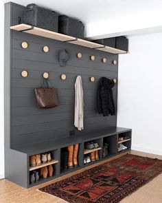 a coat rack with shoes and purses hanging on the wall next to a rug