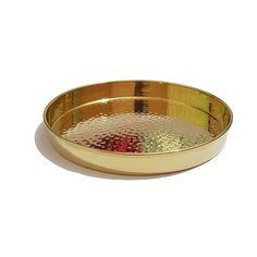 a gold plate with red, yellow and green designs on the rim is sitting on a white surface