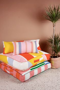 three pillows stacked on top of each other next to a potted plant