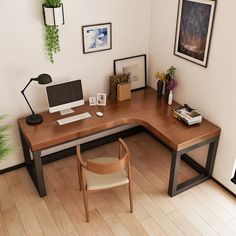 a corner desk with a computer on it in an office space next to a potted plant