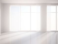 an empty room with large windows and white curtains