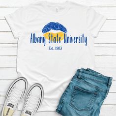 Albany State University Golden Rams T-SHIRT. Be fly and rep your college and school colors in this custom piece. Great unisex design that's flattering for both men and women. This T-shirt fits most customers true to size. It is a soft, relaxed fit. Available T-shirt colors: White, Black, Gray - 100% combed and ring-spun cotton (Bella Canvas 3001) - Fabric weight: 4.2 oz/y² (142 g/m²) - Pre-shrunk fabric - Shoulder-to-shoulder taping - Side-seamed - Retail fit (more tailored with fitted sleeves) College Style Crew Neck T-shirt For College Events, University Logo Cotton T-shirt For College Events, White Crew Neck T-shirt For College Events, College Style Short Sleeve T-shirt For Game Day, Game Day University Logo Short Sleeve T-shirt, White Short Sleeve Top With University Logo, Collegiate White T-shirt With University Logo, White College Style T-shirt With Text Print, White College Style T-shirt