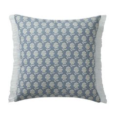 a blue and white pillow with fringes on the bottom, in front of a white background