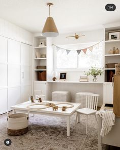 a white table and chairs in a room with bookshelves on the far wall