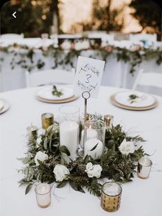 the table is set with candles, flowers and greenery for an elegant wedding reception