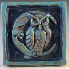 an owl is sitting on top of a blue square tile with a crescent around it