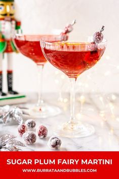 two glasses filled with red liquid sitting on top of a table next to candy canes