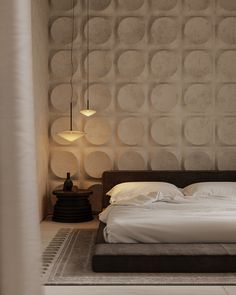 a large bed sitting under a lamp next to a wall mounted light on the side of a bedroom