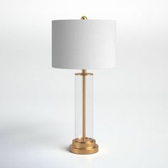 a lamp with a white shade on top of it and a gold frame around the base