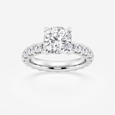 a white gold engagement ring with diamonds on the band and a round cut diamond in the center