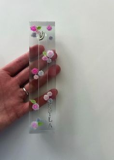 a person's hand holding a clear case with pink and purple flowers on it