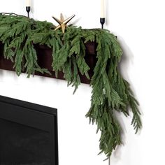 the mantle is decorated with greenery and candles