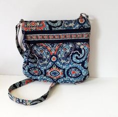 This quilted fabric shoulder or crossbody bag was made for Vera Bradley. It features a blue and orange paisley design. The top has a zip closure. Approximately 11" x 11", it has an adjustable shoulder strap, 2 zippered slip pockets on the front, and a zippered pocket on the inside. The shoulder strap is adjustable and the inside is lined with a contrasting blue fabric. It is in great condition! Wonderful piece for collectors! Free shipping in the USA  Want to see more purses: https://www.etsy.co Quilted Fabric, Blue And Orange, Paisley Design, Blue Fabric, Cross Body Handbags, Vera Bradley, Purses And Handbags, Jewelry Shop, Paisley