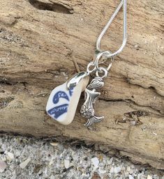 a blue and white ceramic pendant on a wooden piece with gravel around it's edge