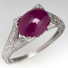 This captivating ring features a pierced and engraved design with milgrain details and is centered with an oval, ruby cabochon, weighing 2.53 carats, in a four-prong setting. The ring measures 7.1mm at the top, rises 7.9mm above the finger, tapering to 1.1mm wide and 0.7mm thick at the base of the shank. This ring is currently a size 5. Vintage Ruby Rings, Antique Cocktail Ring, Ruby Ring Vintage, Ruby Rings, Engraved Design, Ruby Engagement Ring, Red Gemstones, July Birthstone, Vintage Jewels