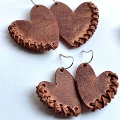 three heart shaped leather earrings on white background