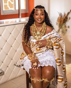 a woman sitting in a chair wearing gold jewelry