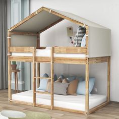 a wooden bunk bed with blue pillows on the bottom and white mattresses underneath it