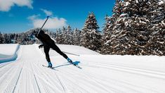 a man riding skis down the side of a snow covered slope next to trees