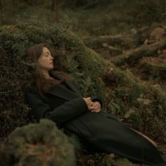 a woman laying on the ground with her arms crossed and head resting on her chest