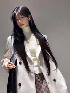 a woman with long black hair wearing a white coat