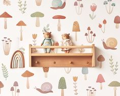 two teddy bears sitting on top of a wooden shelf in front of a mushroom wallpaper