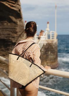 A beach bag to plan a vacation for. Lou is the ultimate summer tote. Made in our signature cane rattan with leather details that elevate it to a handbag. The structured base keeps Lou upright on the sand, so your belongings stay sand-free (as long as no one's tossing pétanque nearby!) and the wider opening gives you extra room for your beach essentials. Pairs perfectly with ocean salty hair and tan lines. Also available in Caramel Rattan. Woven rattan Cow leather straps, trim and base | Magnetic Chic Beach Bag With Bamboo Handle For Travel, Everyday Summer Beach Bag With Bamboo Handle, Casual Beach Bag With Bamboo Handle For Travel, Summer Beach Bag With Bamboo Handle For Everyday, Chic Top Handle Beach Bag For Vacation, Chic Sand Shoulder Bag For Travel, Chic Vacation Beach Bag With Top Handle, Travel Beach Bag With Bamboo Handle, Summer Beach Bag With Leather Handles And Top Handle