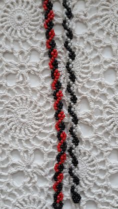 two black, red and white beaded necklaces hanging on a wall next to each other