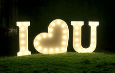 lighted letters spelling out the word i love you in front of a grassy field at night