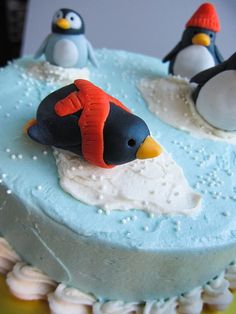 two penguins are on top of a frosted cake