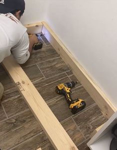 a man laying on the floor with tools in his hand and working on wood planks