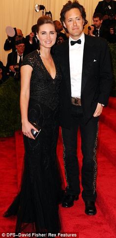 a man in a tuxedo standing next to a woman on a red carpet