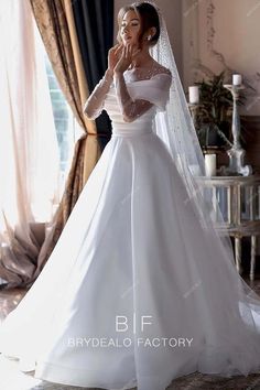 a woman in a white wedding dress with a veil on her head is posing for the camera